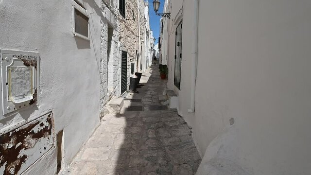 Ostuni, Puglia, Italy. August 2021. POV footage strolling through the white alleys of the historic center: enchanting glimpses full of charm, you advance along the pavement.