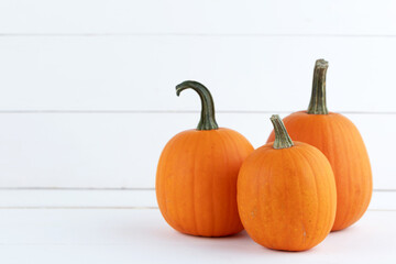 Three pumpkins on white wood