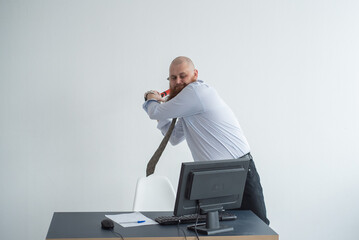 Stressed crazy businessman smashing his computer in office using ax problem concept. The man has problems at work and frustration.