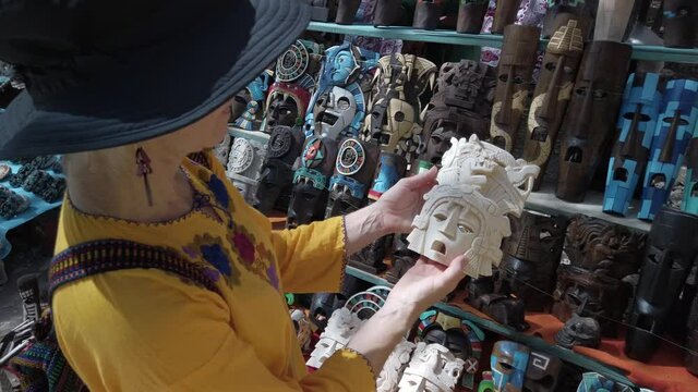 Blonde mature woman looking at tourist souvenirs at Chichen Itza historical park in Mexico.