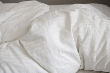 messy and crumpled  natural white bed sheets in bed - obrazy, fototapety, plakaty