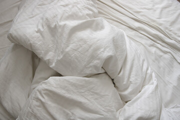 messy and crumpled  natural white bed sheets in bed - obrazy, fototapety, plakaty