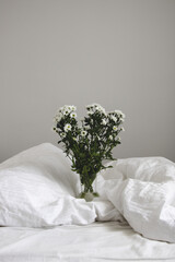 bouquet of white flowers in bed bedroom with  natural bed sheets blanket 
crumpled