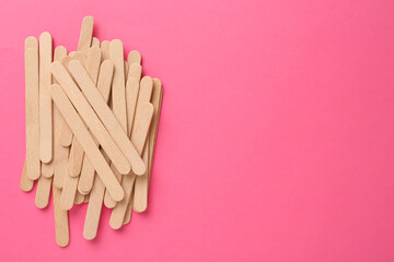 Wooden waxing spatulas on bright pink background, flat lay. Space for text