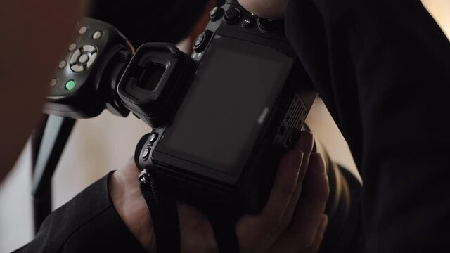 Male photographer takes photographs on a professional camera with flash.