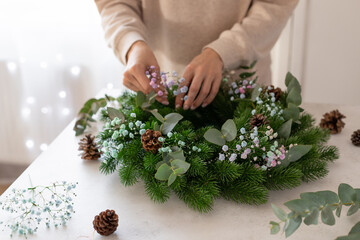 person hands making Christmas wreath with flowers. Christmas, New Year celebration decoration....