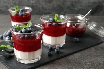 Delicious panna cotta with fruit coulis and fresh blueberries served on grey table. Space for text