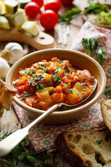 Vegan zucchini and pumpkin stew with the addition of tomatoes and herbs in a bowl, close up view. Healthy and nutritious meal 