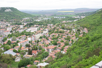 Fototapeta na wymiar Small bulgarian city at the foot of the mountain. Small houses, administrative buildings, parks.