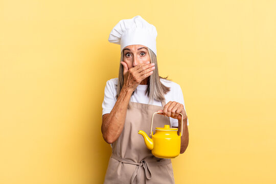 middle age chef woman covering mouth with hands with a shocked, surprised expression, keeping a secret or saying oops and holding a teapot