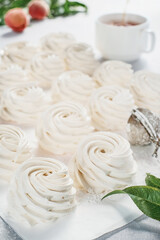 Zephyr dessert close-up, selective focus, sprinkled with powdered sugar. The idea of making marshmallow from peach puree with the addition of agar. White paper background. Tea time