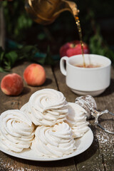 Dessert zephyr (marshmallow) on a white plate, on an old wooden table, afternoon tea in the garden. Airy Russian dessert close up, selective focus.