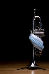 A silver plated piston trumpet with a medical mask on, to represent restrictions on concerts and culture during a pandemic
