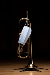A gold plated rotary trumpet with a medical mask on, to represent restrictions on concerts and...