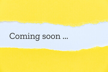 Coming soon phrase typewritten on torn yellow paper background