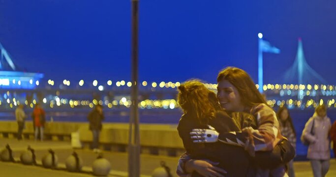 a woman with a bionic hand hugs a friend on a walk through the night city