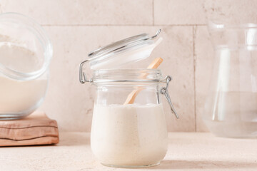 Wheat sourdough starter, flour in glass jar and  water pitcher. Horizontal orientation.