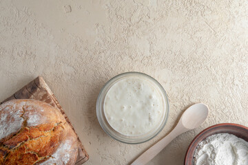 Wheat sourdough starter, flour and homemade bread. Horizontal orientation. Copy space. Flat lay.
