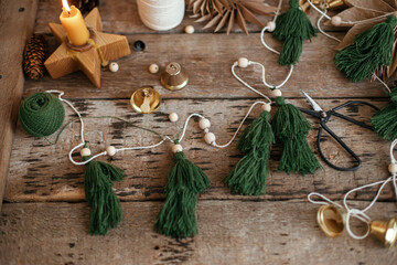 Stylish Christmas fir trees garland, thread, bells, paper stars, ornaments, candle, scissors on...