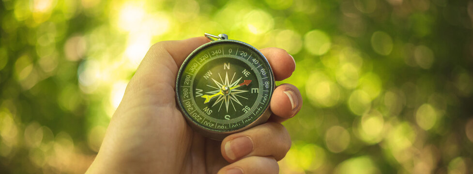 Orienteering in the woods with compass in the hand, banner photo