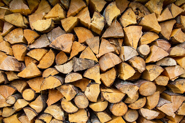 Firewood background of chopped wood for kindling and heating the house close up. Woodpile with stacked firewood ready for winter.