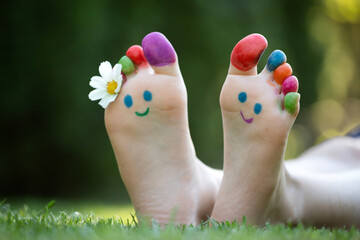 Children's feet with a pattern of paints smile on the green grass.