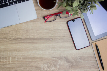 Working space with coffee, computer, notebook and phone on a wooden table. 