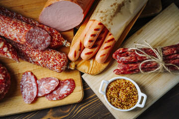 Various types of meat and sausages on wooden table, served on board, closeup. Top view.