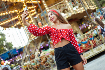 Happy cheerful blonde woman doing selfie and having fun in the amusement park