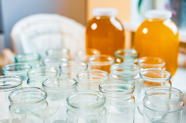 Composition of a large number of jars and three jars of honey standing on a white table against a background of light