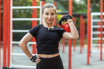 Young athletic woman working out with kettlebell on modern workout ground. Functional outdoor training