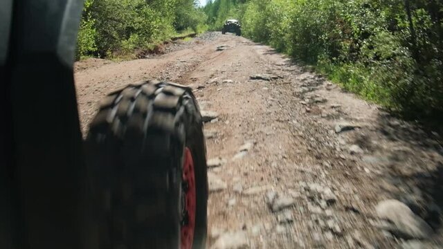 The front wheel of the buggy rides on a rocky road. Rear side view