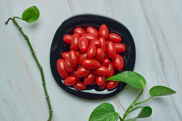 Stack of cherry tomatoes on a plate on a white marble table. Vegetarian food concept.