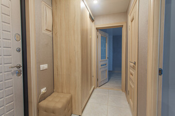 Long and narrow corridor against the background of doors and cabinet, passing through the entire hallway