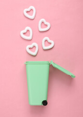 Broken heart concept. Trash can with hearts on pink background
