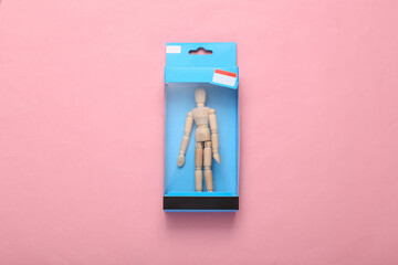 Wooden puppet in packaging on a pink background