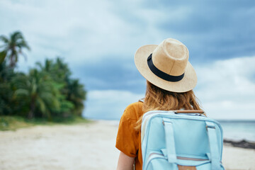 traveler with backpack hat on head and orange sundress tourism back view