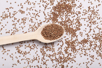 Wooden spoon with dry buckwheat groats on gray background
