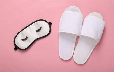 Sleeping mask with eyelashes and slippers on pink background. Top view