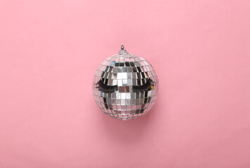 minimal party layout. Mirror disco ball with false eyelashes on a pink background. Top view