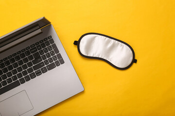 Sleep at work. Concept with sleep mask and laptop on yellow background