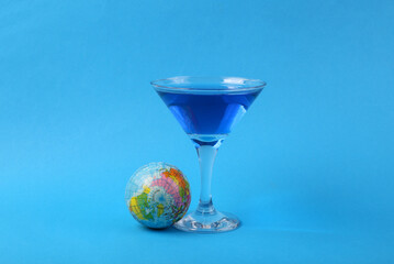 Margarita blue cocktail with globe on blue background. Party concept