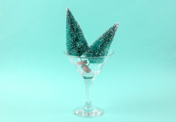 Christmas trees in cocktail glass on blue background. Creative idea. Minimal Christmas party concept.