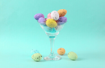 Cocktail glass with colored eggs on blue background. Creative idea. Minimal Easter concept. Concept...