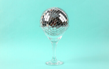 Cocktail glass with disco ball on blue background. Creative idea. Minimal party concept, layout