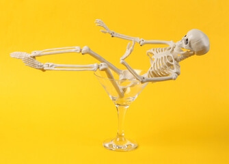 Cocktail glass with skeleton on yellow background. Fresh idea. Minimal party concept, creative layout