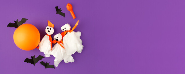 Halloween paper decorations on bright purple violet background. Black bats, ghosts, balloons....