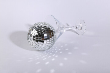 Cocktail glass with disco ball on bright gray background. Creative idea. Minimal party concept....