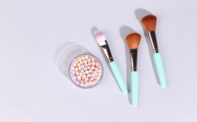 Obraz na płótnie Canvas Powder balls in box with make-up brushes on gray background