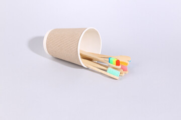 Wooden toothbrushes in cardboard cup on gray background